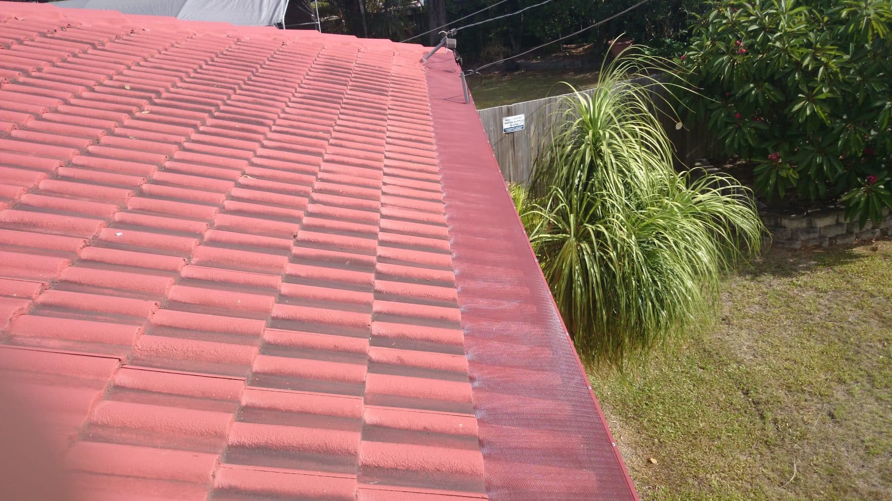 Gutter guard mesh installed on a red terracotta tile roof